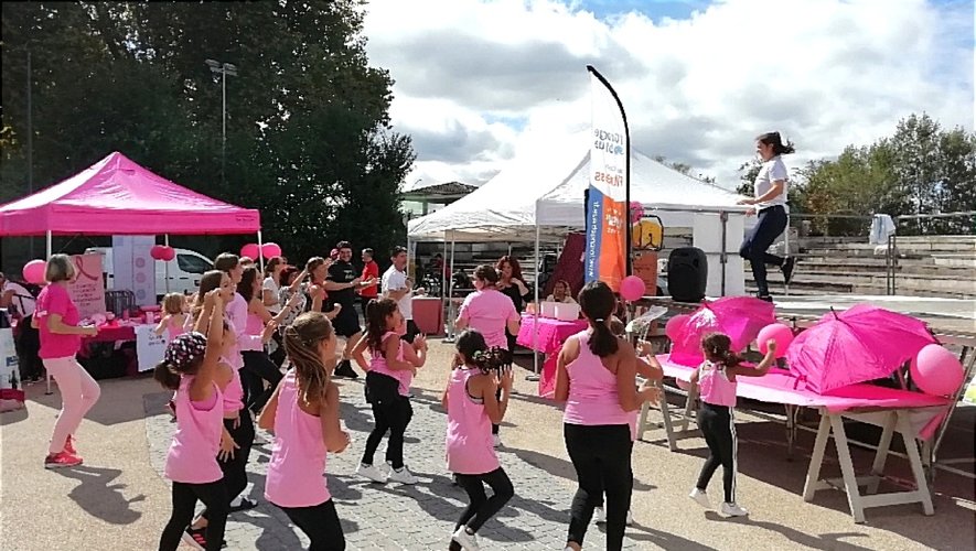 Photo d'un groupe de jeunes enfants habillés en rose qui font du sport, encouragés par une animatrice sur la scène en face